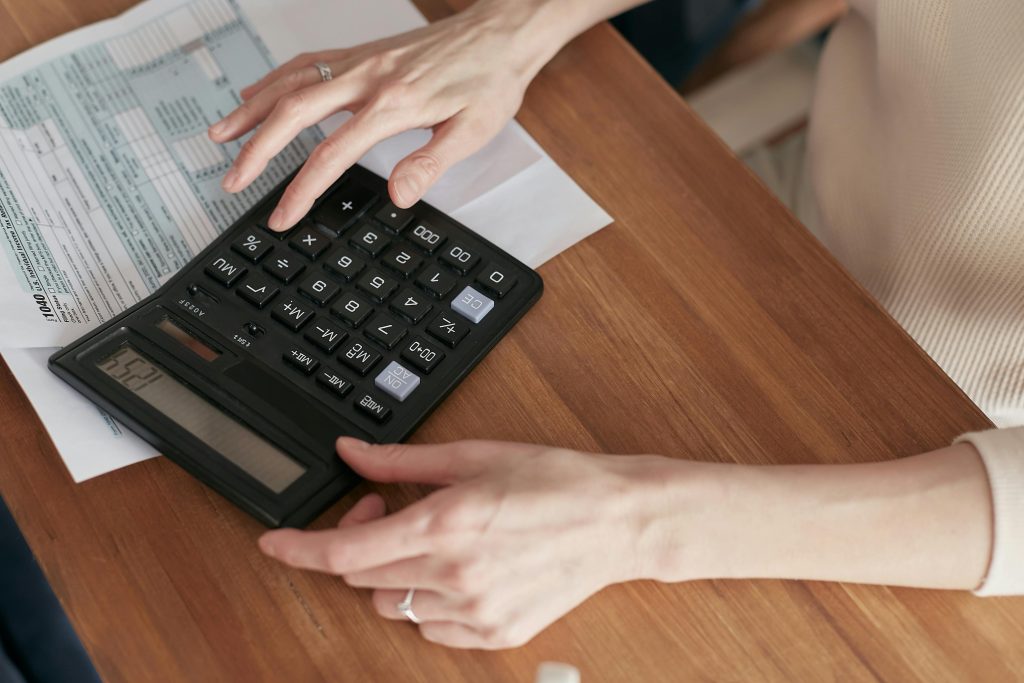 pexels-photo-6963017-6963017 Close-up of a woman using a calculator and reviewing bills at home.