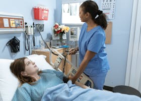 Nurse providing care to a patient in a hospital room with medical equipment.